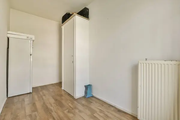 an empty room with wood floors and white walls, including a radiac heater on the right side