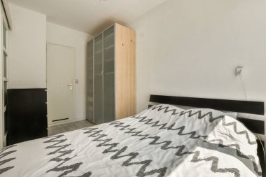 Yatağı, şifoniyeri ve aynası olan bir yatak odası yatağın önünde siyah ve beyazdır.