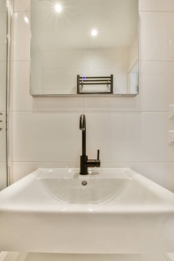 Yanındaki duvarda lavabo ve ayna olan bir banyo cam duş kapısı görüntüsüdür.