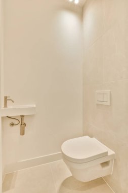 Duş odasında, duvarlarında ve zemininde bej fayanslar olan beyaz bir tuvalet.