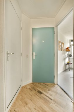 Odanın ortasında mavi kapısı ve ahşap zemini olan boş bir oda beyaz bir duvardır.