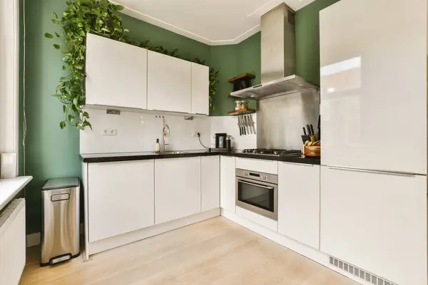 a kitchen with white cupboards and green wallpaper on the walls in an apartment or residential area, which can be used as