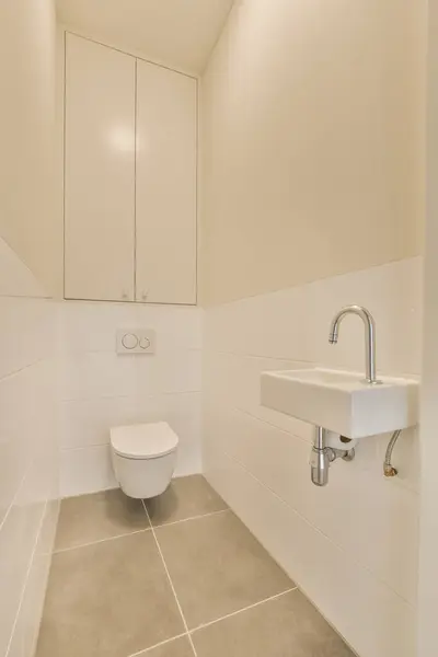 a small bathroom with white walls and tile flooring, including a toilet in the corner next to the sink