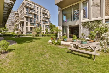 Ön bahçesinde yeşil çimenler ve ağaçlar olan bir apartman kompleksi.