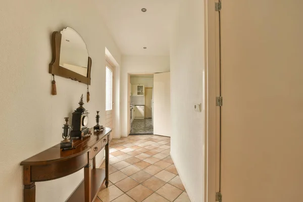 a hallway with a mirror on the wall and an open door leading to another room that has a tiled floor