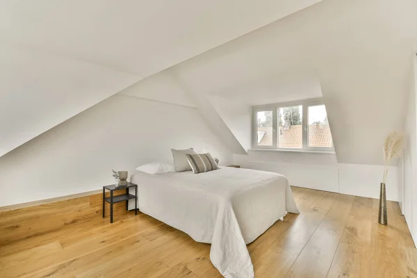 a bedroom with white walls and hardwood flooring in the room, there is an empty bed on the right side