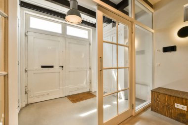 Beyaz bir odanın içinde, kapılarda, pencerelerde ve döşemelerde ahşap süslemeler var.