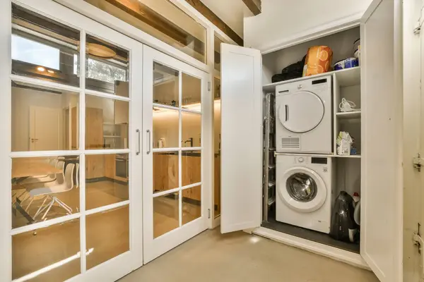 a laundry room with a washer, dryer and washing machine in the corner between the door to the kitchen
