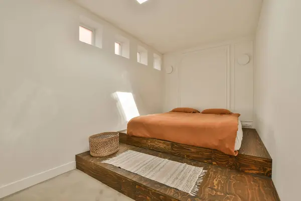 a bed in the corner of a room with white walls and wood flooring on the bottom part of the wall