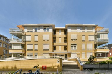 Önünde iki motosiklet olan bir apartman dairesi ve soldan ikinci kata çıkan merdivenler.