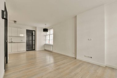 Odasında ahşap döşeme ve beyaz duvarlar olan boş bir oturma odası çok temiz, ama mobilya yok.