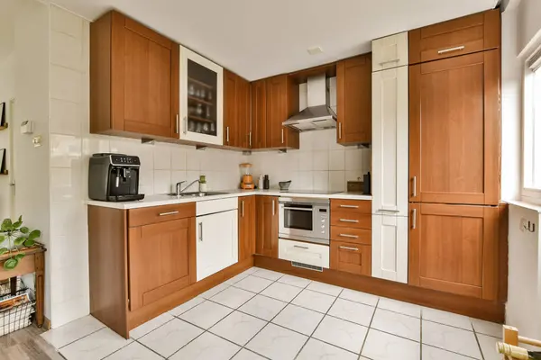 a kitchen with wood cabinets and white tiles on the floor in front of the oven, microwave and dishwasher