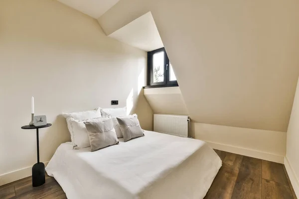 a bed in the corner of a room with white walls and wood flooring on the other side of the room