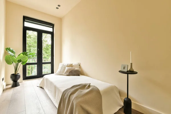 a bedroom with two beds and a plant in the corner next to the bed is an open window that looks out onto the balcony