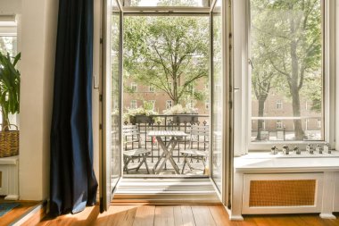 Ahşap döşemeli, verandaya açılan cam kapaklı yemek masası ve sandalyeli bir oda.