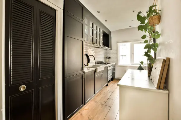 a kitchen with black shutters on the door and wood flooring in the room below is a plant hanging over the sink