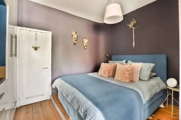 a bed in a room with purple walls and white trim around the headboard, blue bedspremn