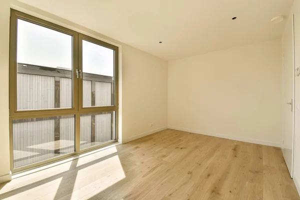 an empty room with wood flooring and sliding glass doors that open to the outside, looking out onto the street