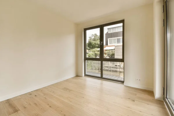 an empty living room with wood floor and sliding glass door that opens onto the balcony area to let in natural light