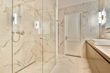 Zarif mermer dokular, şık armatürler ve geniş bir duş tasarımı içeren modern bir banyonun çarpıcı iç tasarımı. Parlak ve davetkar bir ortam..
