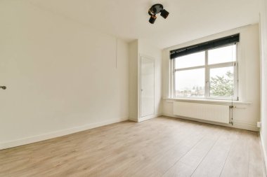 Geniş ve parlak bir oda. Temiz hatları ve minimalist tasarımı var. Hafif ahşap döşemeleri ve geniş pencereleri var..