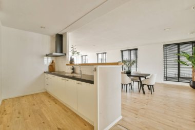 Şık ve şık bir mutfak ahşap zemin, doğal ışık ve taze bir atmosfer için işlevsel elementler ve yeşillik karışımı modern tasarımı sergiliyor..