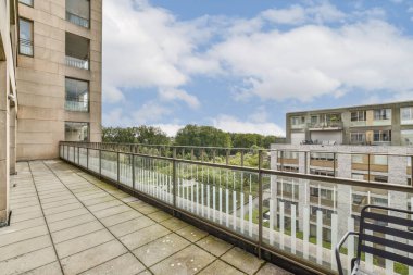 Geniş bir balkon, yemyeşil ve mavi gökyüzüne tepeden bakan çağdaş bir tasarıma sahip. Rahatlamak ve dışarıda yaşamaktan zevk almak için mükemmel..