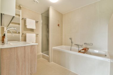 Pürüzsüz ve çağdaş bir banyo. Küvet, duş ve şık eşyalar. Rahatlamak için sakin ve zarif bir ortam yaratıyor..