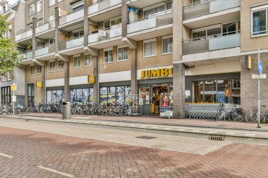 Park halindeki bisikletlerle ve modern apartmanlarla çevrili Jumbo adında bir marketin bulunduğu canlı bir alışveriş alanı..