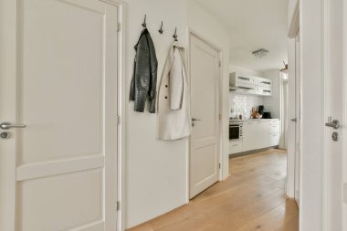 Modern dekorların sergilendiği, iki kapısı ve minimalist bir mutfağı olan şık bir iç mekan koridoru. Temiz ve davetkar bir tasarım alanı geliştirir.