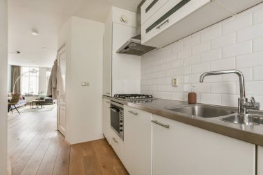 Pürüzsüz, modern bir mutfak. Minimalist tasarım unsurları var. Açık bir düzen, şık bir dolap ve doğal ahşap döşemeler..