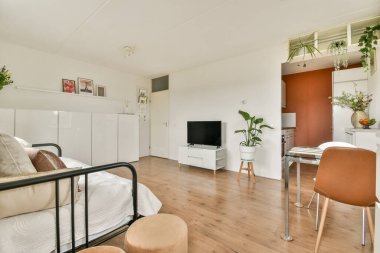 Minimalist dekor, ahşap döşemeler ve zevkli döşemelerle dolu parlak ve havadar bir oda rahatlama ve yaşam için rahat bir atmosfer yaratıyor..