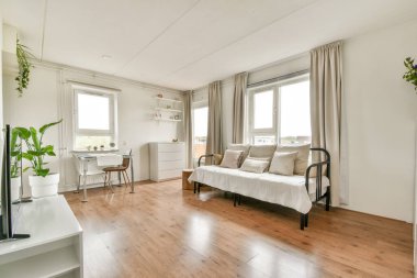 Kanepe, bitki ve doğal ışığın geniş pencerelerden içeri aktığı parlak ve havadar minimalist bir oturma odası, huzurlu bir atmosfer sağlıyor..