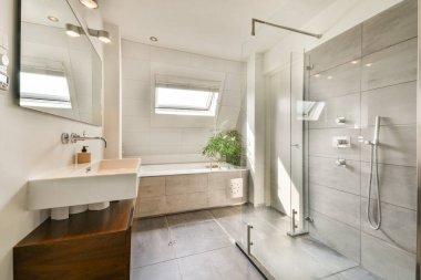Parlak ve modern bir banyo, cam bir duş, şık eşyalar, ve tavan penceresinden gelen doğal aydınlatma uzaya zarafet katıyor..