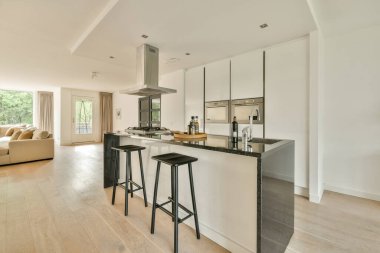 Merkezi bir ada barı, gösterişli dolaplar ve geniş ve davetkar bir yemek alanı yaratan modern bir mutfak..