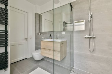 Şık ve çağdaş bir banyo, cam bir duş, ahşap kibir ve şık ve işlevsel bir yer için zarif eşyalar sergiliyor..
