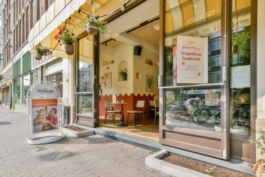 Canlı bir vejetaryen sandviç dükkânı açık havada oturma izni, neşeli bir dekor ve canlı kentsel çevreyle çevrili bir menü tabelası..