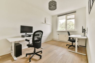 Pencereden giren iki masa, modern sandalyeler ve doğal ışığın yer aldığı parlak ve havadar bir ofis üretken bir atmosferi teşvik ediyor..