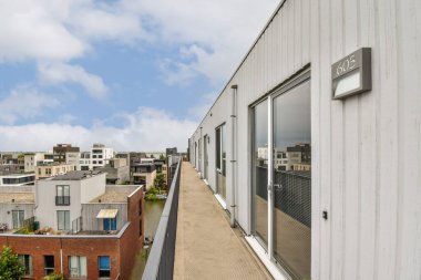 Çağdaş kentsel tasarımı vurgulayan, yeşil ve parlak gökyüzü ile çevrili, balkonları olan modern konut binalarının çarpıcı bir görüntüsü.