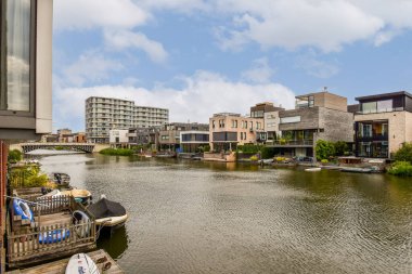 Şık modern evler, yemyeşil ve mavi gökyüzünün ortasındaki çağdaş mimariyi gözler önüne seren sakin bir nehir kıyısı..