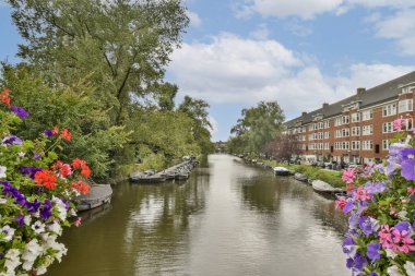 Su yolu boyunca yemyeşil ve renkli çiçeklerin bulunduğu pitoresk bir kanal sahnesi, sakin ve davetkar bir atmosfer sağlıyor..