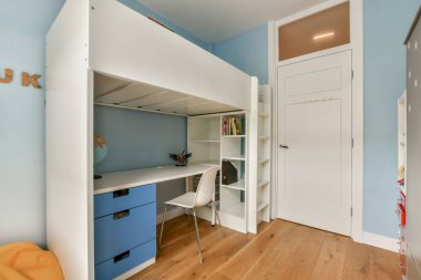 Çatı katı bir yatak odası, minimalist çalışma masası ve canlı renkler, konfor ve yaratıcılık için davetkar ve işlevsel bir yaşam alanı yaratıyor..