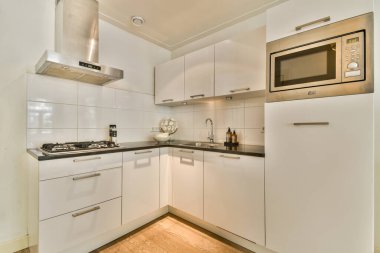 Beyaz dolaplar, paslanmaz çelik aletler ve minimalizm ve işlevselliği ön plana çıkaran temiz ve modern bir mutfak..