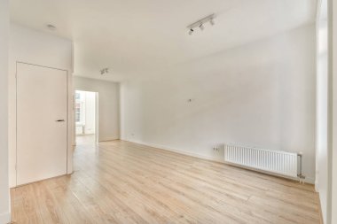 Açık renkli ahşap döşeme ve basit tasarım elementlerinin yer aldığı parlak ve ferah bir modern iç mekan. Oda boş, temiz çizgilerini vurguluyor..