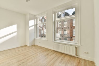 Geniş pencereli geniş bir oda geniş doğal ışık, ahşap döşeme ve basit bir tasarım sağlıyor. Rahat bir yaşam alanı yaratmak için ideal.