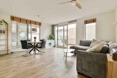 Geniş pencereli, şık bir kanepe ve zarif mobilyalarla dolu parlak ve havadar bir oturma odası. Rahatlamak için mükemmel bir karşılama atmosferi yaratıyor..