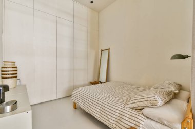 Huzurlu ve modern bir yatak odası basit bir tasarımı sergiliyor. Yatak, çizgili yatak, ayna ve temiz çizgiler, sükunet ve rahatlığı vurguluyor..