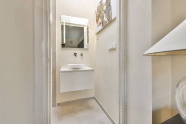 Zarif bir leğen ve aynanın yer aldığı modern bir banyo, basitlik ve zarafeti vurgulayan minimalist bir tasarım yaklaşımı sergiliyor..