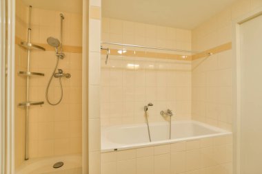 Küveti ve duşu olan şık, modern bir banyo. Temiz çizgiler ve sakin bir atmosfer için nötr tonlarla zarif bir şekilde tasarlanmış..