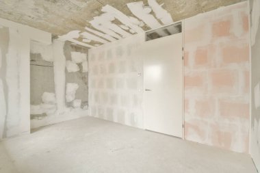 Tamamlanmamış duvarları ve farklı bir kapısı olan modern bir mimari tarzın sergilendiği boş bir oda. Boşluk ham dokuları ve asgari tasarım elementlerini vurgular.